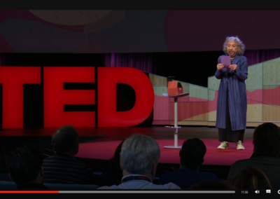 Zrzut ekranu z TED - prelegentka w niebieskim płaszczu, czarnej sukience i zielonych trampkach