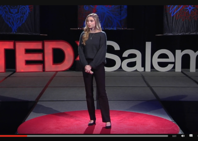 Zrzut ekranu z TED - prelegentka w czarnych butach, czarnych spodniach i grafitowym swetrze