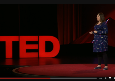 Zrzut ekranu z TED - prelegentka w granatowej sukience w kwiaty, legginsach i mokasynach